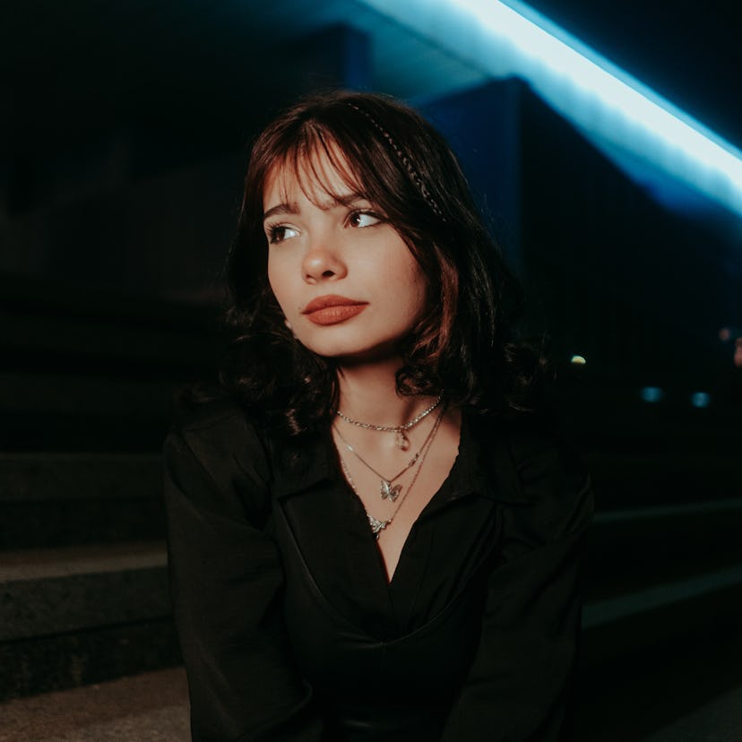 Young woman surrounded by blue neon lights during Neptune retrograde 2022.