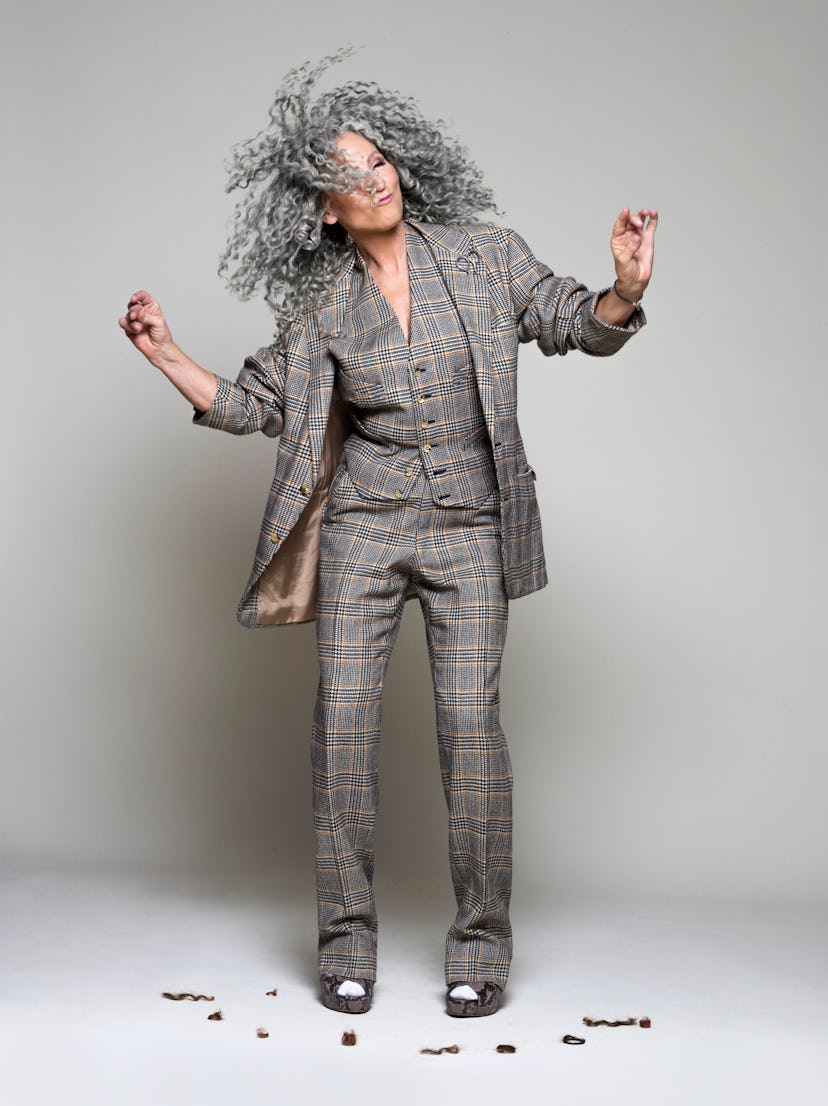 A portrait of Lorraine Massey dancing with her curly hair, and scissors in hand