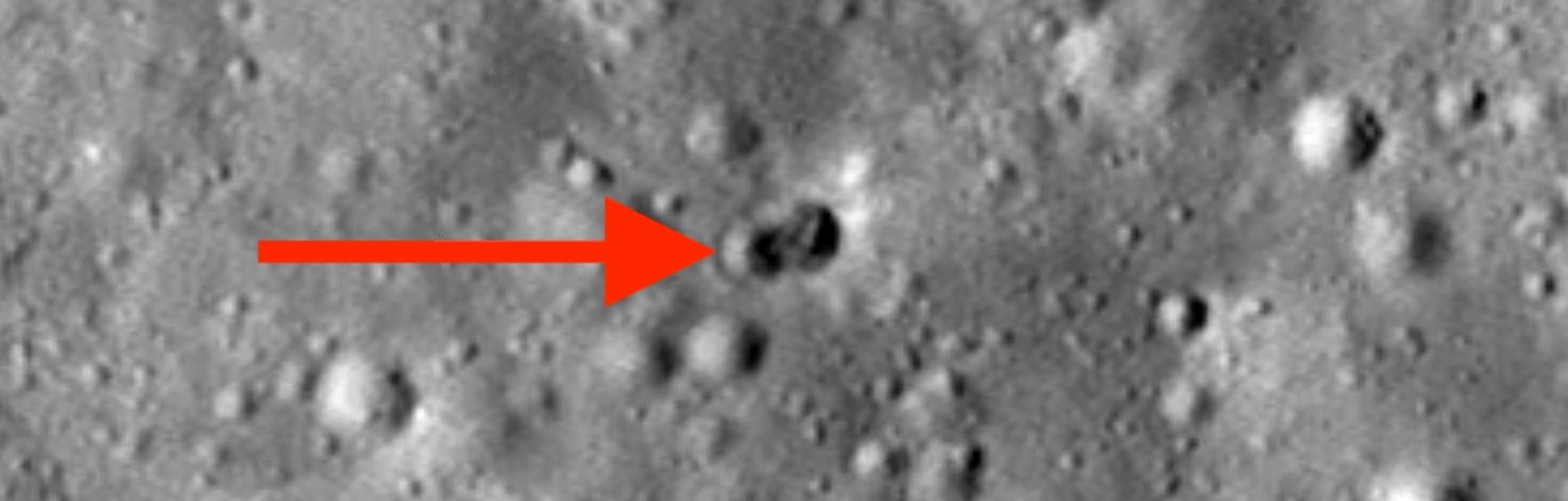 Crater image with a red arrow pointing at the site of a rocket booster crash