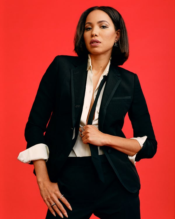 Jurnee Smollett in a black suit with suspenders that she is pulling on and a white shirt