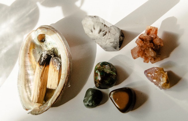 Abalone shell with burning palo santo incense next to an assortment of healing crystals. Here's how ...