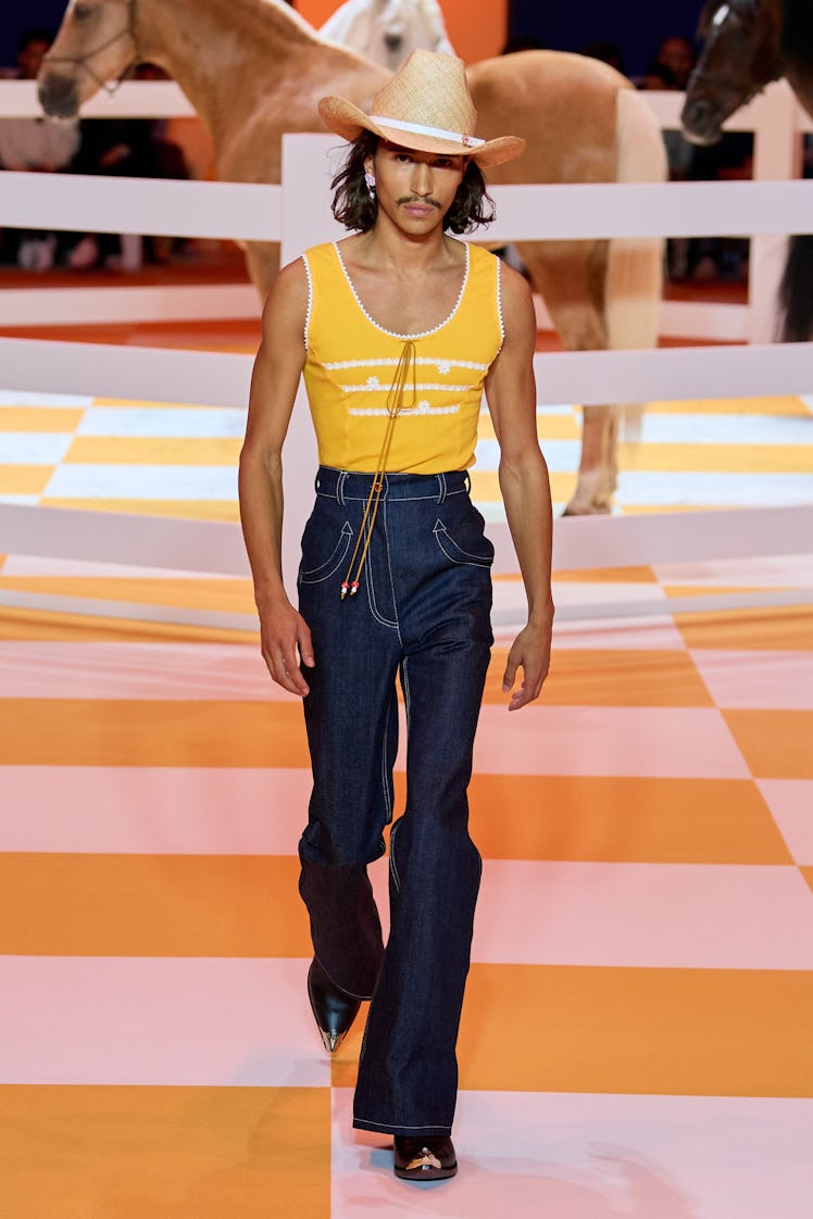 A model wearing Casablanca, with a cowboy hat, yellow tank top, high-waisted denim jeans and pointed...