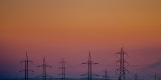 Power transmission lines stand against the sky at sunset.