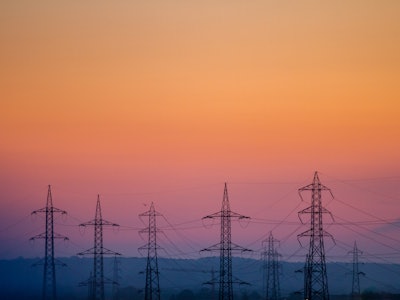 Power transmission lines stand against the sky at sunset.