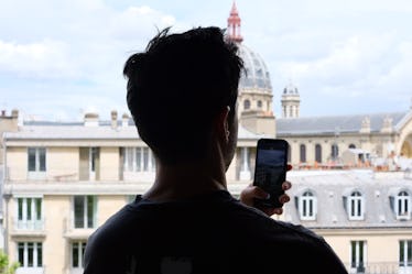 Comedian Paul W. Downs Shares His First Fashion Show Experience 2 Paul looking out over Paris, taking a picture with his phone.
