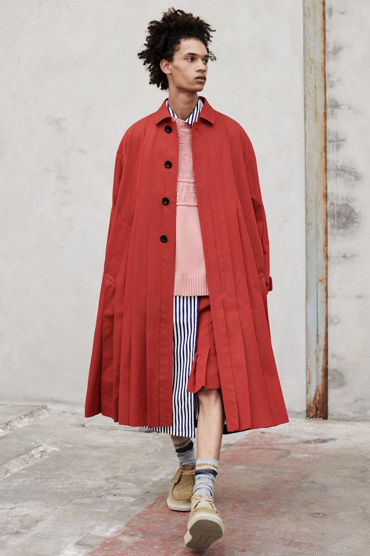 A model wearing a Sacai red coat with a pink shirt and red skirt