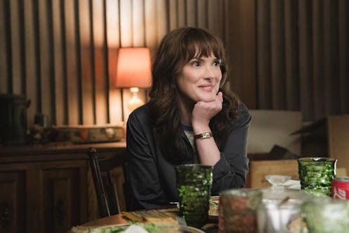 Winona Ryder sitting at a table during a scene from "Stranger Things" 