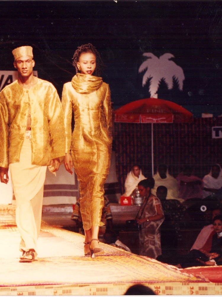three models walking down the runway in gold African-inspired looks