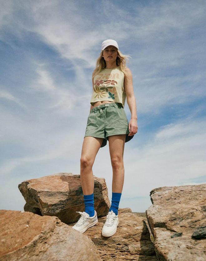 model standing on rocks wearing green madewell hiking shorts