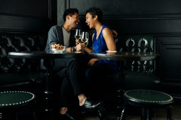 Couple drinking in a booth while asking fun questions to help learn more about their partner.
