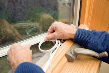 Hands sealing crack on window
