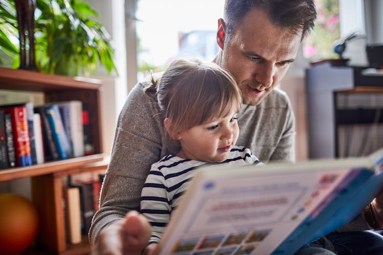 A dad reading a book with his young daughter.