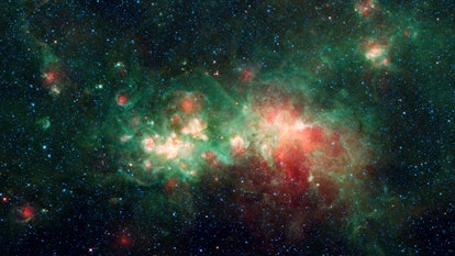 A cloud of red, green, and gold gas glowing in the darkness of space