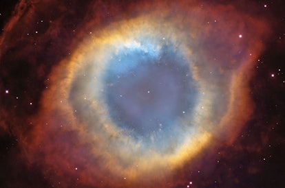 A round cloud of gas fades from blue to green to yellow to red against the blackness of space.
