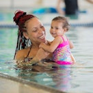 A mother holds her baby in a swimming pool.