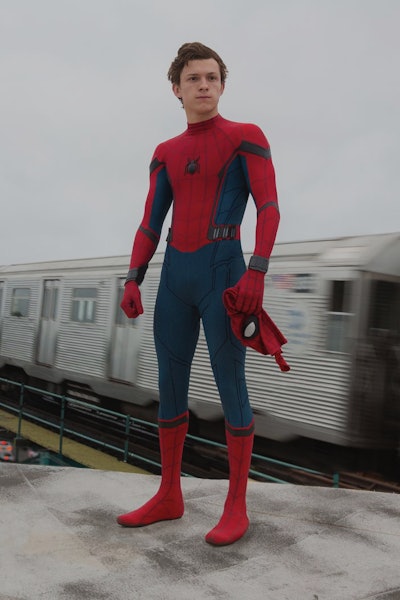 Tom Holland as Spider-Man from the MCU standing on the concrete block while a train is passing next ...