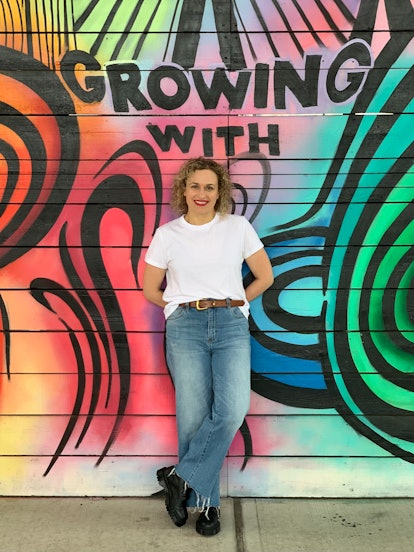 curly haired woman with mural behind her