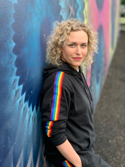 Curly haired woman in rainbow sweatsuit.