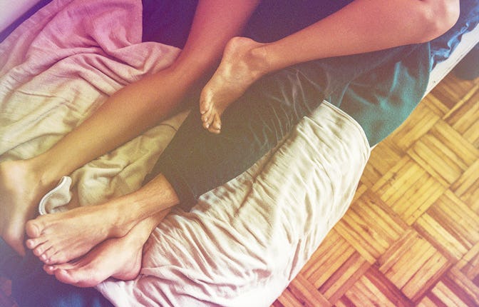 A man and a woman lying in bed with their legs intertwined before having sober sex