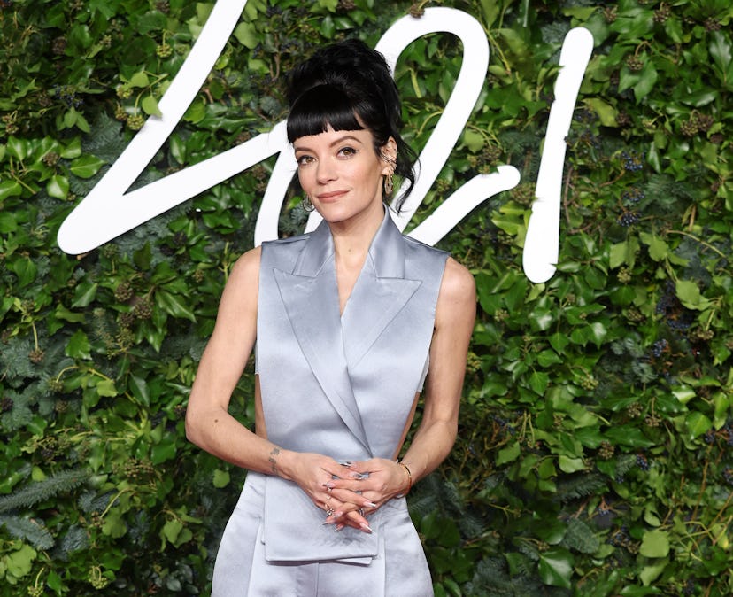 Lily Allen standing against a leafy backdrop