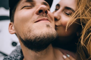 Man smiling with woman kissing him.