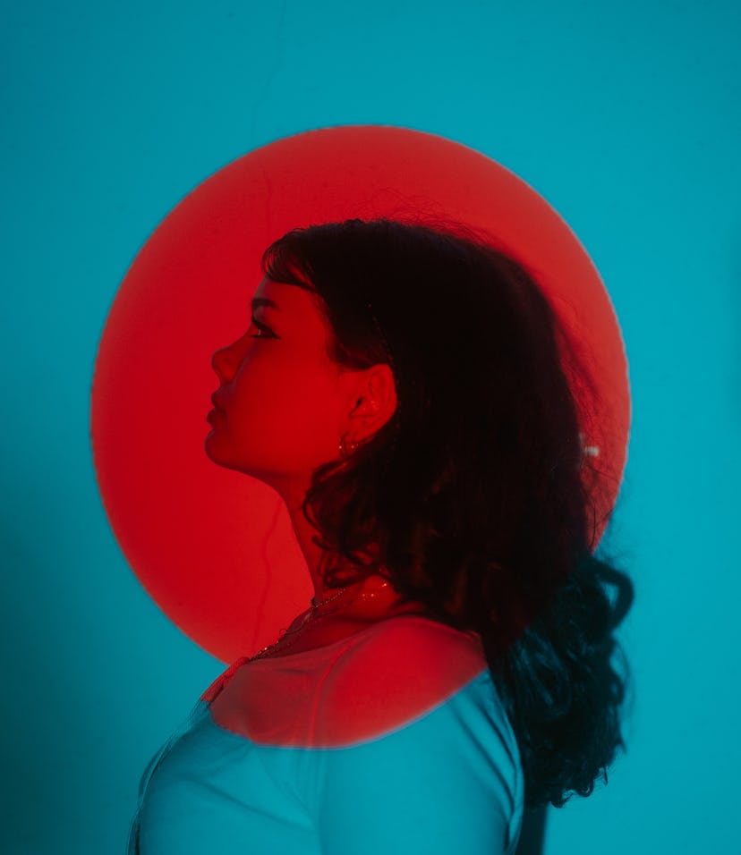 Young woman in front of the full moon in Sagittarius (aka the Super Strawberry Moon) on June 14, 202...