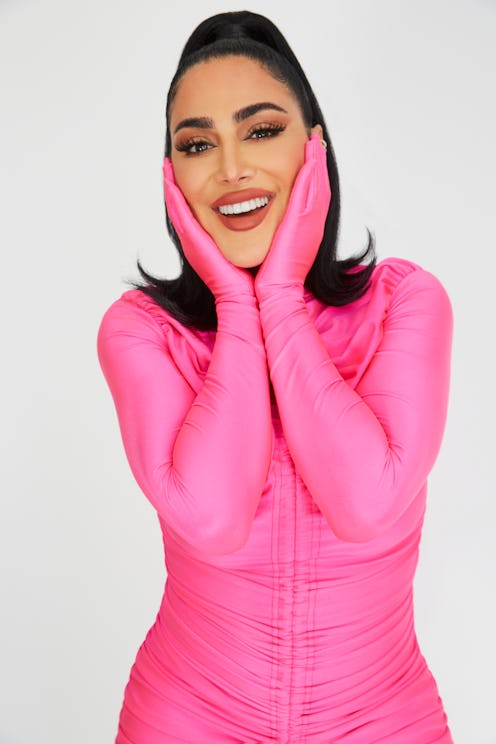 Huda Kattan posing in a pink overall