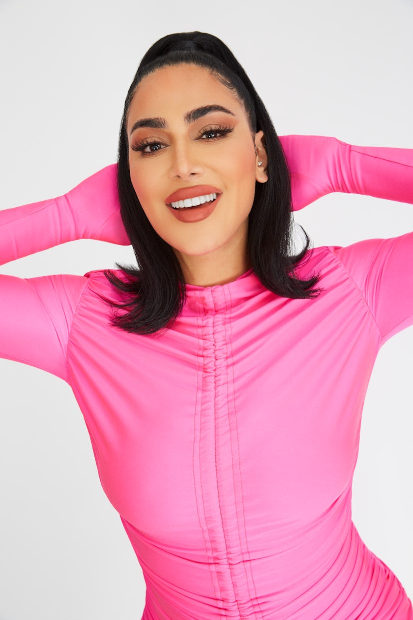 Huda Kattan posing in a pink overall
