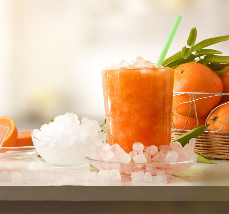 Persimmon and Yuzu Bourbon Slush in a glass with ice next to it