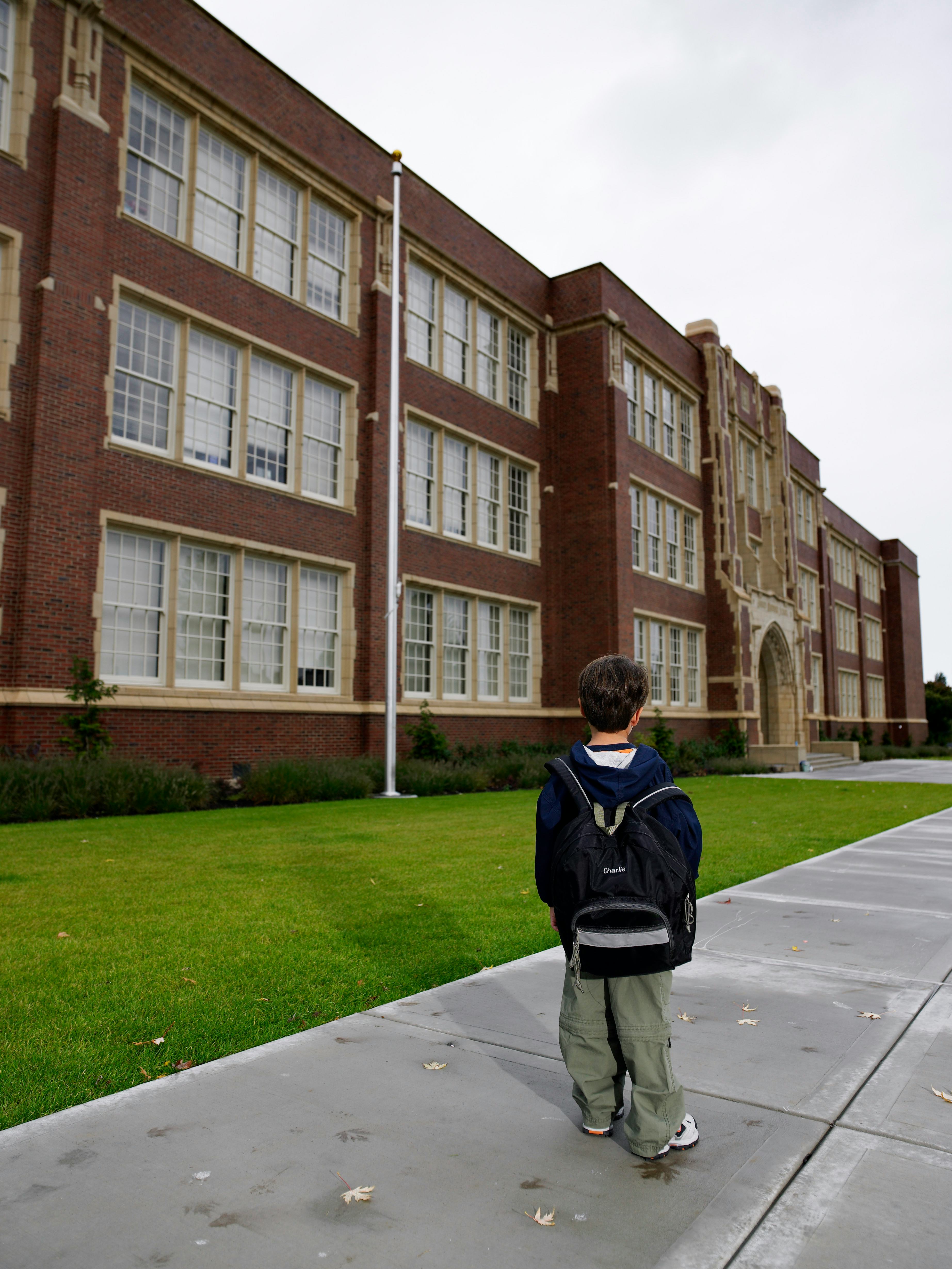 A child standing outside of a school.