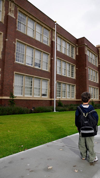 A child standing outside of a school.