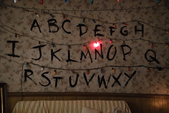 Christmas lights hang above an alphabet written on a wall in 'Stranger Things.'