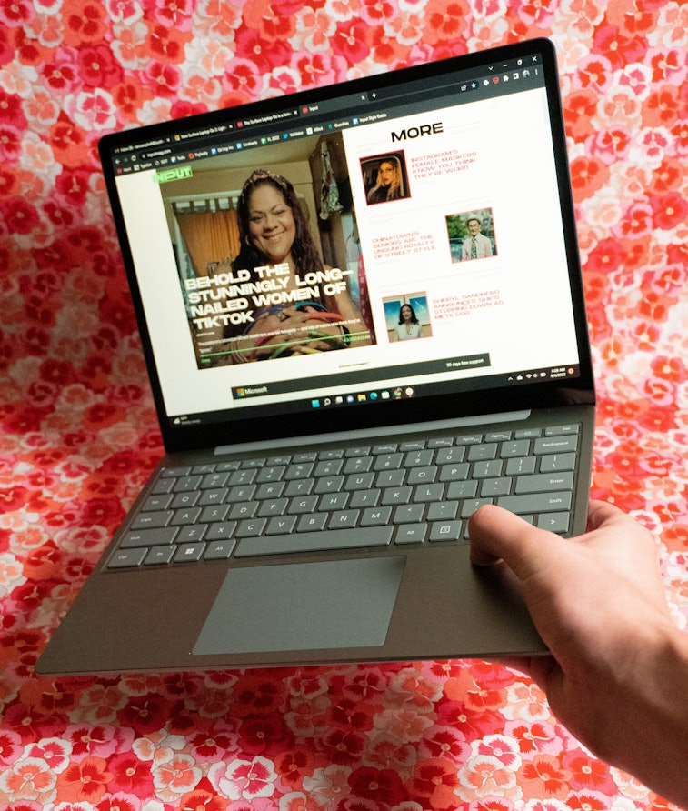 The Surface Laptop Go 2 held open in one hand.