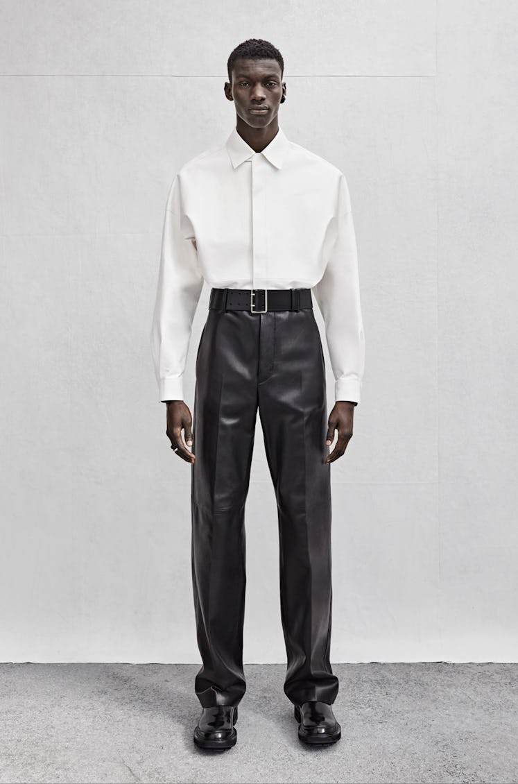 A model wearing an Alexander McQueen white button down shirt and leather pants