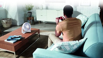 Man playing video games with Honeywell fan on table