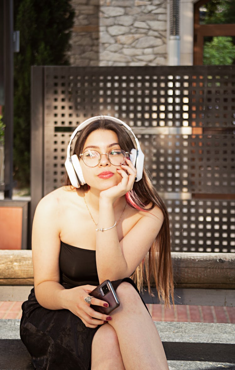 Young woman listening to music, wondering how many full moons are in a year.