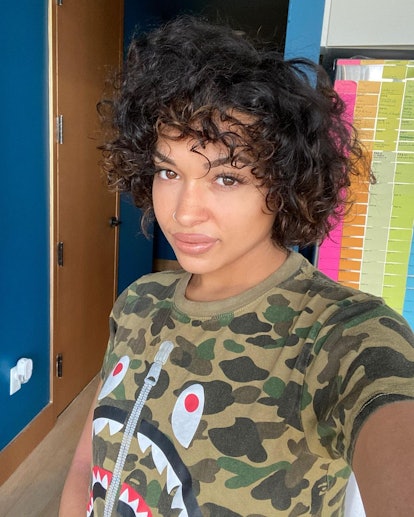 Princess Nokia wearing a camo shirt with a fake zipper and a monster face on it