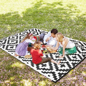 Family having picnic on Sand Mine reversible plastic straw rug, a patio decor find