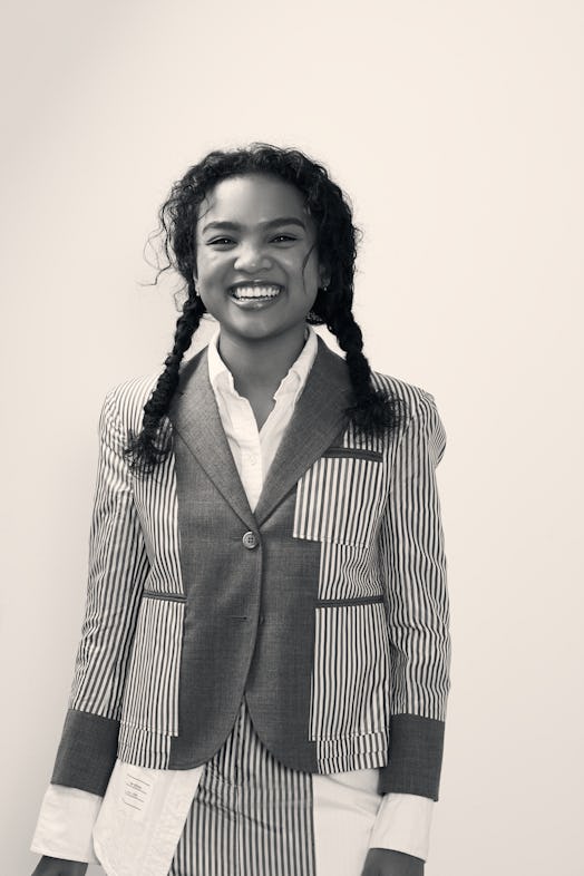 Mia Isaac smiling in a blazer, shirt and dress with stripes in black and white