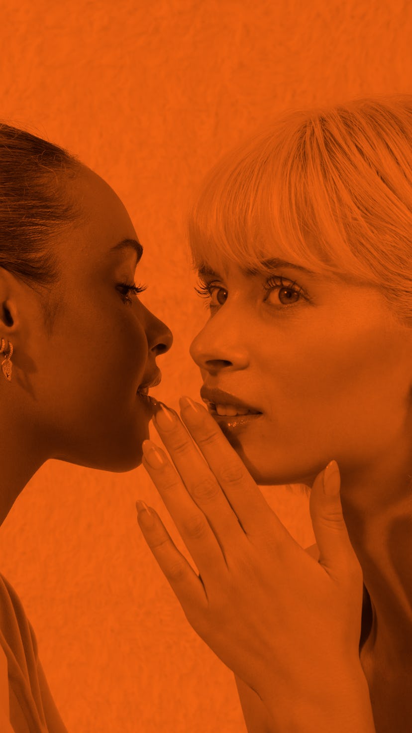 Two female friends whispering to each other