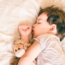 A young boy sleeping with a stuffed animal.