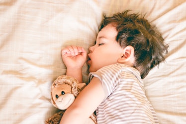 A young boy sleeping with a stuffed animal.