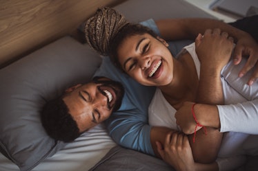 A wife and husband laughing in bed.
