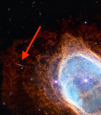 red arrow pointing to the left of a nebula where a small edge on galaxy is visible