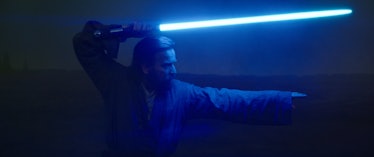 Ewan McGregor holds his blue lightsaber above his head in Obi-Wan Kenobi Episode 6