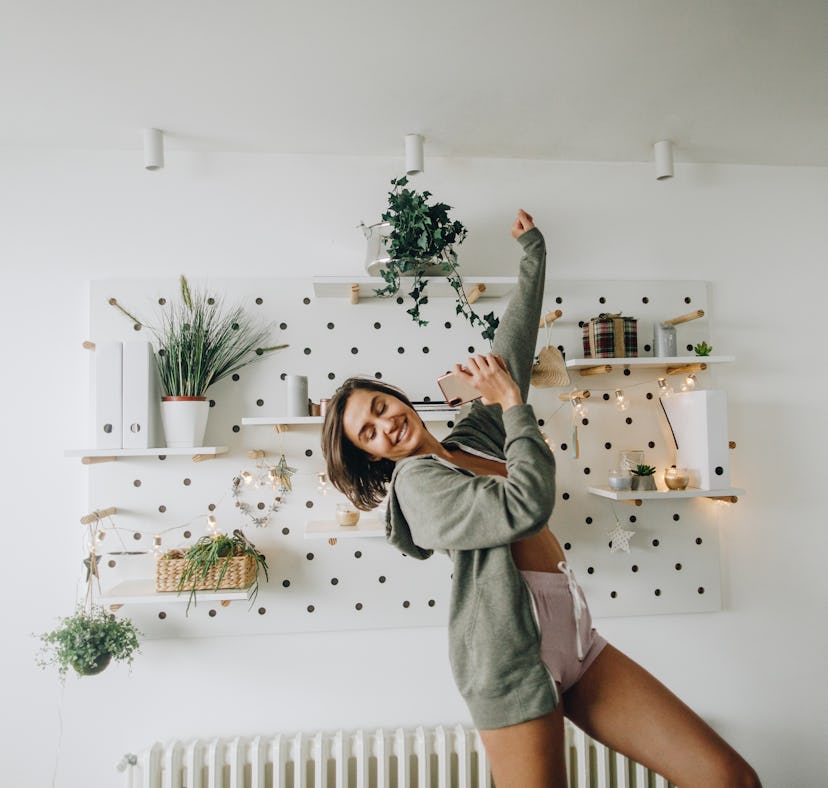 Young woman dancing on her bed after shopping Amazon Prime Day 2022 deals on home organization produ...