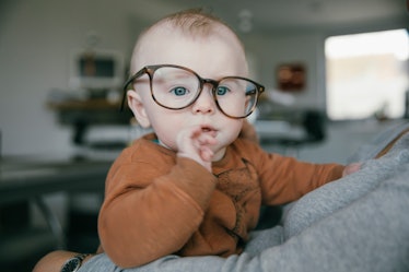 A baby with a big head wearing tilted glasses.