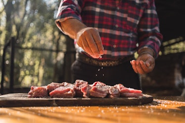 A man salting meat for the barbecue.