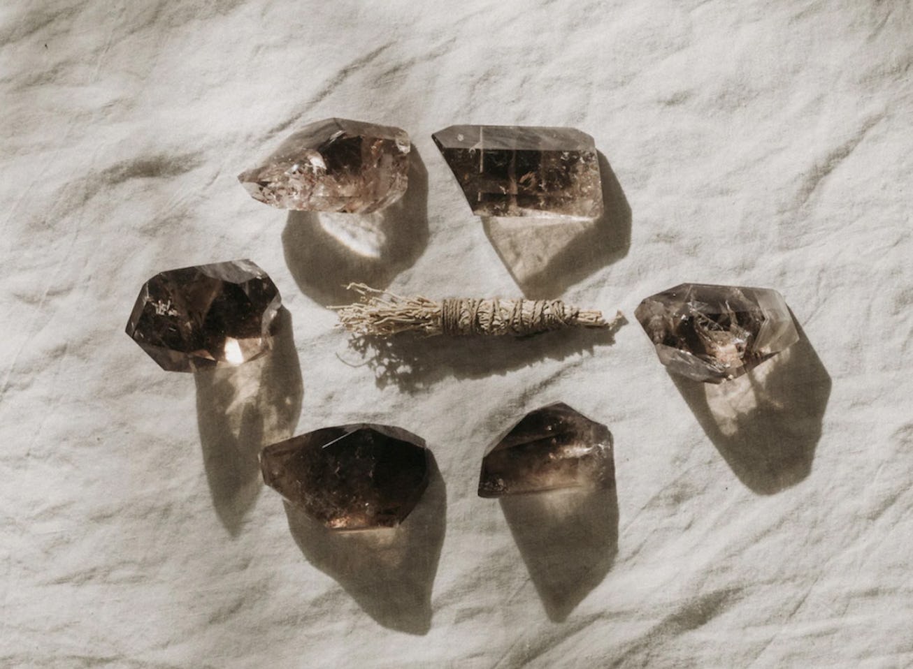 Flat lay of smoky quartz crystals, great for empaths, around an herb bundle
