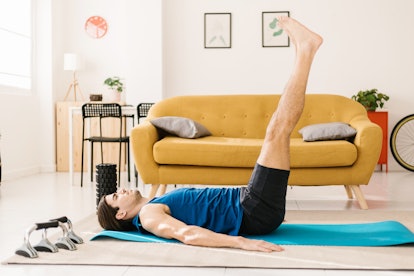 一个男人仰面躺在瑜伽垫上，双腿朝天。